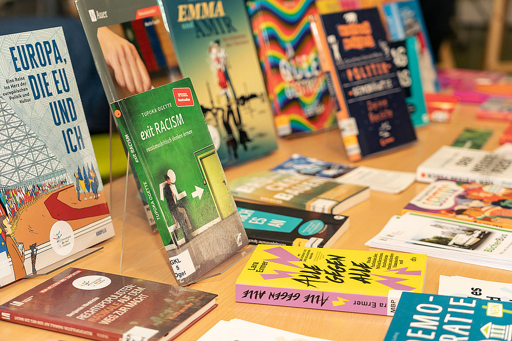Verschiedene Bücher mit buntem Cover zu den Themen Politik, Demokratie, Populismus und Rassismus liegen auf einem Tisch.
