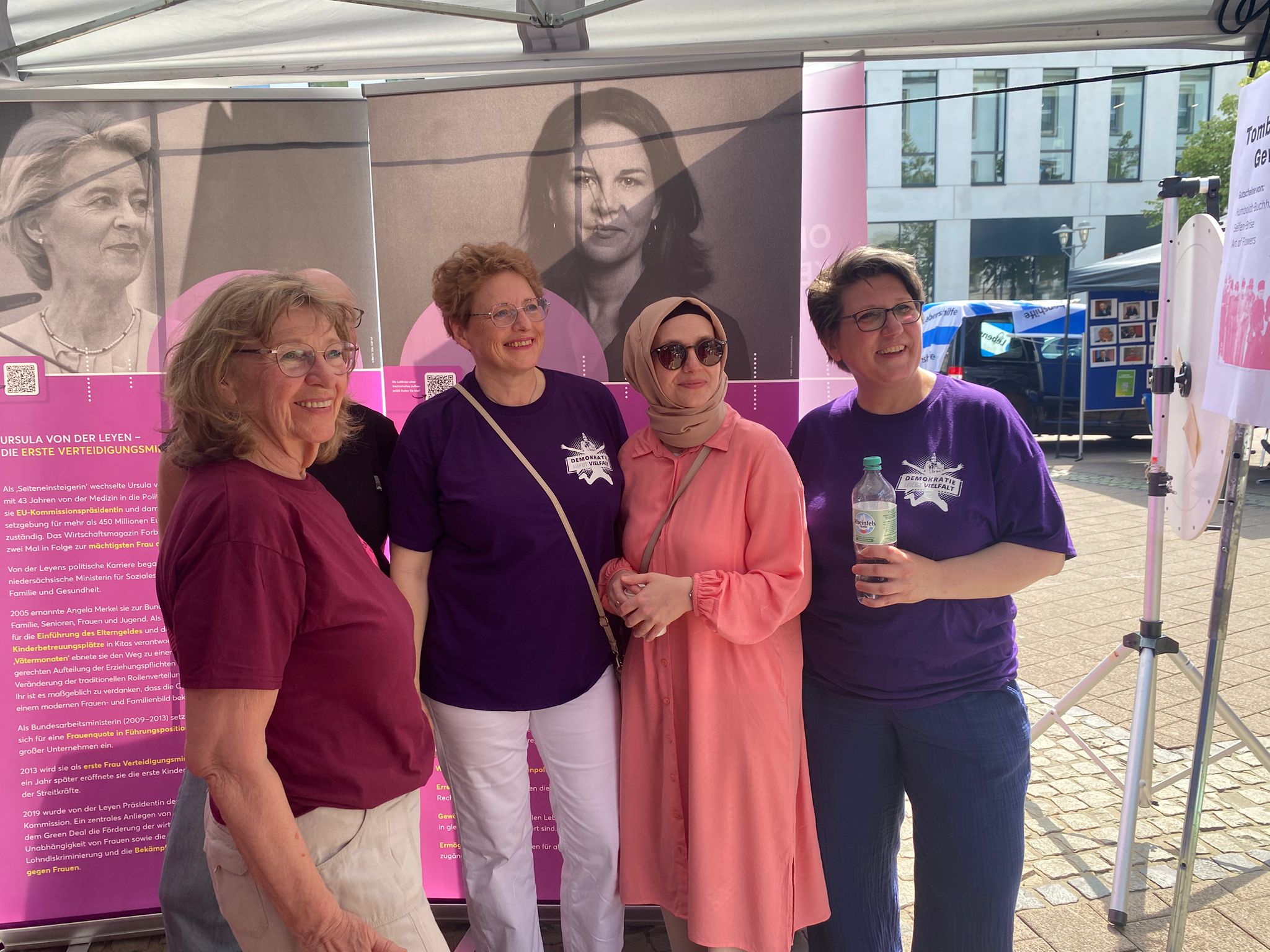 Vier Mitgleider der Initiative Frauen für Demokratie lassen sich in ihrer Ausstellung 100 Jahre Frauenwahlrecht auf dem Willy Brandt Platz fotografieren.